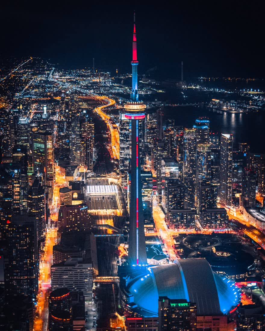 A city at night seen from above, lit streets threading between towers