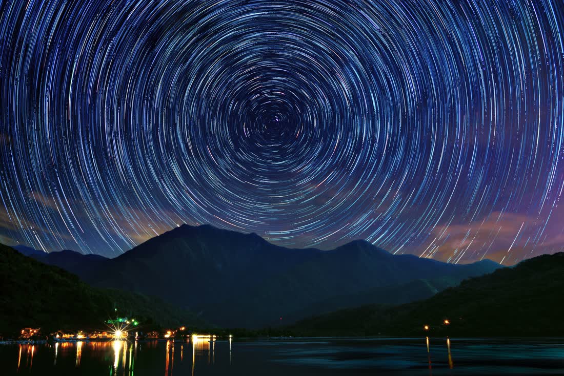 Star trails circling above a mountain lake